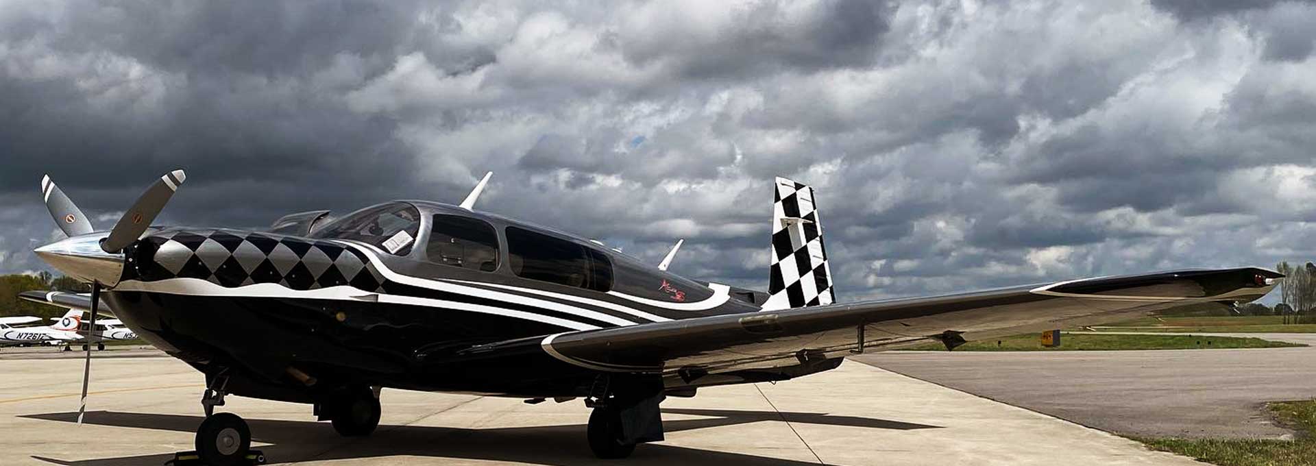 Single prop plane with checkered paint job at KCMD dark clouds overhead