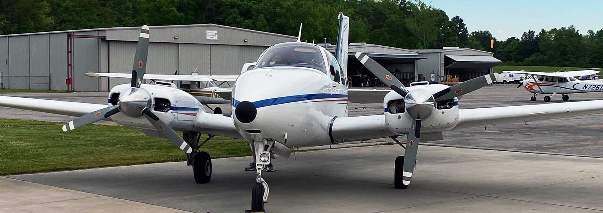 Twin Prop Plane at KCMD others in the background with a hangar