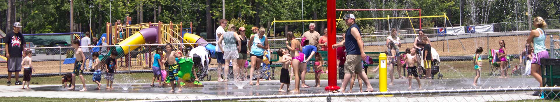Sportsman lake park splash pad with a gathering playing in the water
